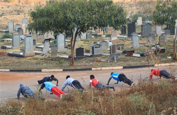 Varias personas hacen gimnasia el 25 de julio del 2015 en el cementerio de Warren Hills en Harare, Zimbabue. Muchos entusiastas de la preparación física aprovechan las zonas mejor cuidadas del camposanto para hacer ejercicios. (AP Foto/Tsvangirayi Mukwazhi)