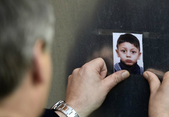 Un hombre se pega una imagen retrato de niño bosnio perdido llamado Mohamed en una pared en la Oficina Estatal de Salud y Asuntos Sociales en Berlín (LAGeSo) el 29 de octubre de 2015. La policía alemana arrestó a un hombre sospechoso de haber secuestrado a los cuatro años de edad, refugiados y dijeron que encontraron el cuerpo de un niño en su coche. AFP PHOTO / TOBIAS SCHWARZ