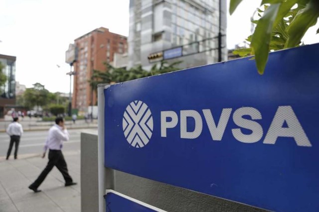 Personas caminan cerca de un cartel de PDVSA, en una de sus gasolineras en Caracas, 28 de octubre de 2015. La estatal Petróleos de Venezuela (PDVSA) denunció el miércoles ser el centro de una "campaña de desprestigio" internacional, luego que medios informaron que autoridades de Estados Unidos detectaron un supuesto esquema de sobornos por al menos 1.000 millones de dólares para ganar contratos de la firma. REUTERS/Marco Bello