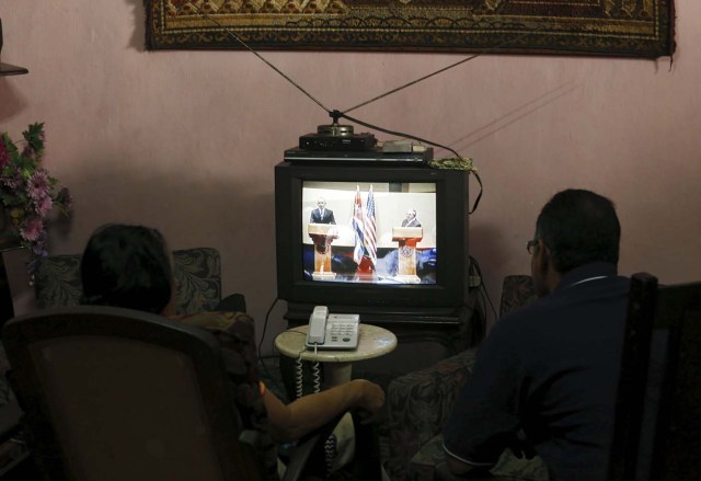 A couple watches on television as U.S. President Barack Obama (L) and his Cuban counterpart Raul Castro hold a joint news conference in Havana, March 21, 2016. REUTERS/Stringer EDITORIAL USE ONLY. NO RESALES. NO ARCHIVE TPX IMAGES OF THE DAY