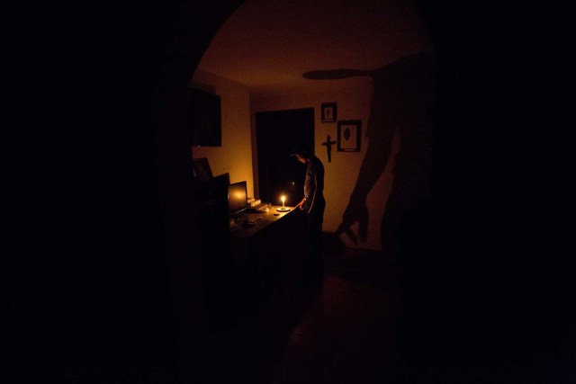 En esta fotografía del sábado 23 de abril de 2016, un niño ilumina su casa con una vela durante un apagón de 24 horas, en el vecindario El Calvario de El Hatillo, en las afueras de Caracas, Venezuela.  El gobierno venezolano anunció el martes 26 de abril la decisión de reducir a solamente dos días la semana laboral en el sector público, al menos por dos semanas para enfrentar la crisis energética generada por la sequía que afecta a la represa del Guri. (Foto AP/Fernando Llano)