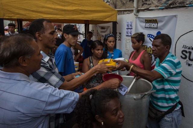 CAR08. CARACAS (VENEZUELA), 10/09/2016.- Habitantes comen de un sancocho comunal hoy, sábado 10 de septiembre del 2016, en la ciudad de Caracas (Venezuela). En el barrio la Unión, ubicado en la favela más grande de América Latina asentada en el este de Caracas, se preparó hoy un gran "sancocho" como se le conoce en Venezuela a la sopa cocinada con varios tipos de verduras y carnes, para alimentar a los vecinos, muchos de ellos con varios días de hambre. EFE/MIGUEL GUTIÉRREZ