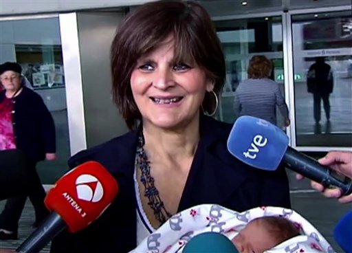 En esta imagen captada de la televisión el martes 18 de octubre de 2016 se ve a Lina Álvarez saliendo del Hospital Lucus Augusti, en la ciudad de Lugo, España, con su hija recién nacida en brazos. La mujer de 62 años dio a luz a una bebé sana y animó a otras mujeres en edad avanzada a hacer lo mismo que ella si es que lo desean. (Atlas TV vía AP)