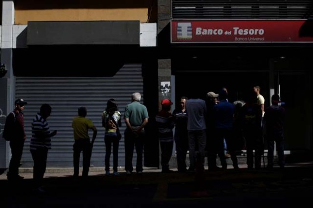 People line up to withdraw cash from a Banco del Tesoro branch in Caracas, Venezuela December 2, 2016. REUTERS/Ueslei Marcelino
