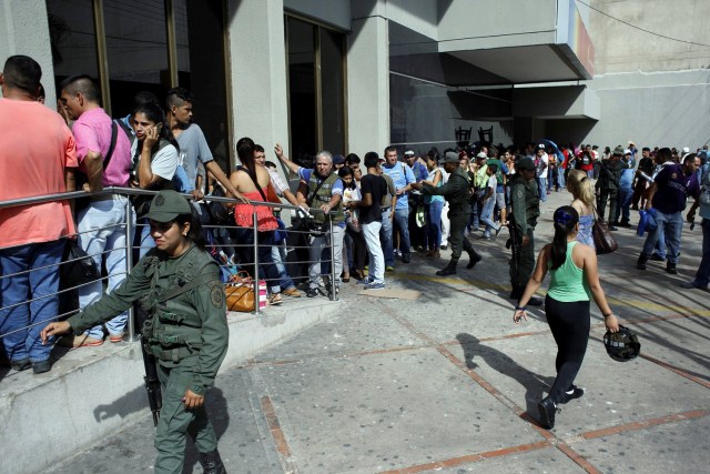 Venezuelan soldiers stand guard next to people lining up to get into a Banco de Venezuela branch in San Antonio del Tachira, Venezuela December 13, 2016. REUTERS/Carlos Eduardo Ramirez