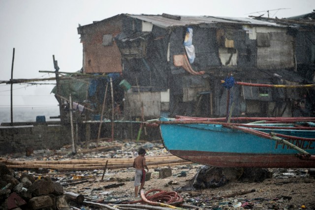 A boy runs for cover as it rains near the breakwater in Baseco, Manila on December 26, 2016. Typhoon Nock-Ten, which made landfall on the eastern island province of Catanduanes on December 25, is forecast to move westward towards the country's heartland, packing winds of 215 kilometres (134 miles) per hour. / AFP PHOTO / NOEL CELIS