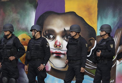 En esta fotografía del lunes 9 de enero de 2017, policías vigilan durante una protesta de miles de personas contra el gobierno del presidente Enrique Peña Nieto debido al alza de 20% a la gasolina en la Ciudad México. En la imagen al fondo se aprecia un muro con arte callejero. Diversas partes de México han sido escenario de manifestaciones desde el alza a la gasolina el 1 de enero y la inconformidad ha devenido en ocasiones en actos de violencia, incluida una ola de saqueos durante varios días. (AP Foto/Rebecca Blackwell)