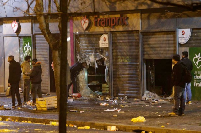 People gather by a vandalized Franprix supermarket during protest in Bobigny, a district of northeast Paris, to denounce police brutality after a black man was allegedly sodomised with a baton during an arrest while in their custody in Paris on February 11, 2017. A 22-year-old black youth worker named as Theo, a talented footballer with no criminal record, required surgery after his arrest on February 2, 2017 when he claims a police officer sodomized him with his baton. One officer has been charged with rape and three others with assault over the incident in the tough northeastern suburb of Aulnay-sous-Bois which has revived past controversies over alleged police brutality. / AFP PHOTO / GEOFFROY VAN DER HASSELT