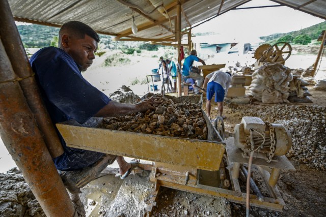 A man works at a stone crusher machine in a gold mine in El Callao, Bolivar state, southeastern Venezuela on February 25, 2017. Although life in the mines of eastern Venezuela is hard and dangerous, tens of thousands from all over the country head for the mines daily in overcrowded trucks, pushed by the rise in gold prices and by the severe economic crisis affecting the country, aggravated recently by the drop in oil prices. / AFP PHOTO / JUAN BARRETO / TO GO WITH AFP STORY by Maria Isabel SANCHEZ