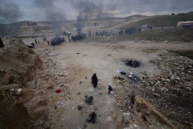 Iraquíes desplazados que huyeron de sus hogares en Mosul se calientan alrededor de fogatas cerca de Badush