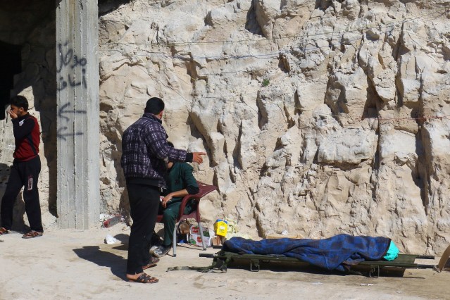 ATTENTION EDITORS - VISUAL COVERAGE OF SCENES OF INJURY OR DEATH People stand near a dead body, after what rescue workers described as a suspected gas attack in the town of Khan Sheikhoun in rebel-held Idlib, Syria April 4, 2017. REUTERS/Ammar Abdullah