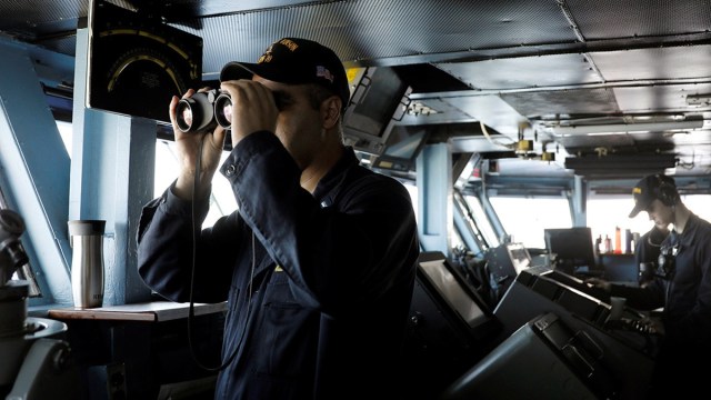 Un miembro de la Armada estadounidense mira a través de unos prismáticos a bordo del USS Carl Vinson durante un ejercicio rutinario en el Mar de China Meridional.
