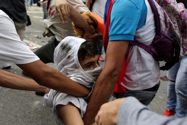 An injured opposition supporter receives help from others after he gets hit by a riot police armoured vehicle while clashing with riot police during a rally against Venezuelan President Nicolas Maduro in Caracas, Venezuela May 3, 2017. REUTERS/Marco Bello