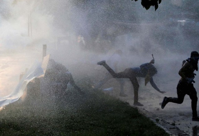 Opposition supporters are hit by a water canon while clashing with riot security forces during a rally against President Nicolas Maduro in Caracas, Venezuela, May 18, 2017. REUTERS/Marco Bello