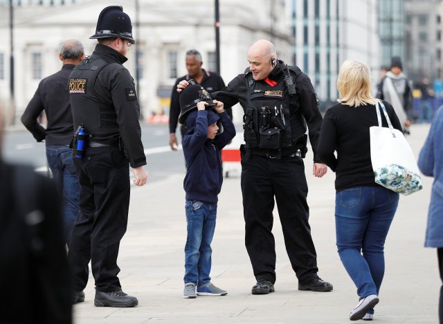 A boy tries on a City of London police officer's helmet as he poses for a souvenir picture on London Bridge in central London, Britain, June 5, 2017. REUTERS/Peter Nicholls