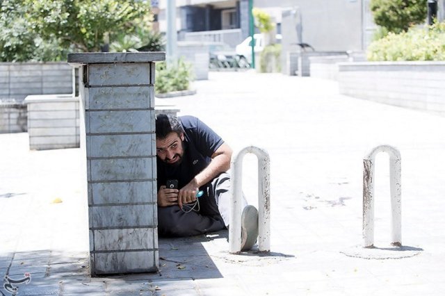 A man takes cover during an attack on the Iranian parliament in central Tehran, Iran, June 7, 2017. Tasnim News Agency/Handout via REUTERS ATTENTION EDITORS - THIS PICTURE WAS PROVIDED BY A THIRD PARTY. FOR EDITORIAL USE ONLY. NO RESALES. NO ARCHIVE.
