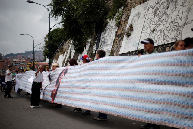 Demonstrators hold a banner made from three thousand two-bolivar-bills, that is equivalent approximately to $1 according to the black market exchange rate, in Caracas, Venezuela, June 10, 2017. Picture taken June 10, 2017. REUTERS/Ivan Alvarado