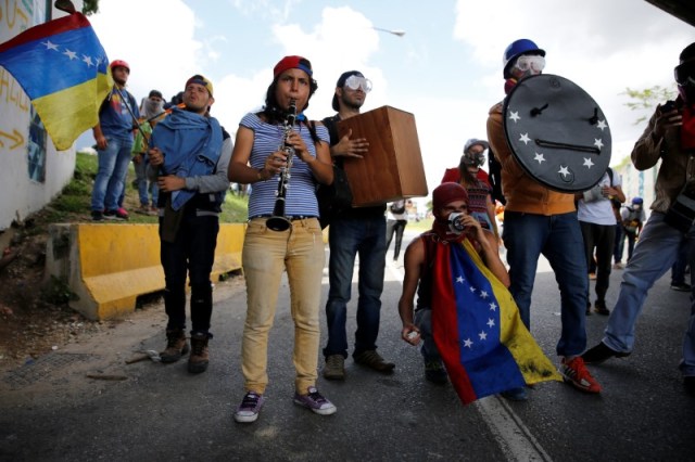 Manifestantes tocan instrumentos mientras se reúnen en una marcha contra el gobierno de Nicolás Maduro, en Caracas, el 19 de junio de 2017. Unas 20 personas se acuestan y levantan por sorpresa en medio de un transitado bulevar de Caracas y comienzan a recitar algunas frases mientras otros muestran el extracto de un poema escrito con letras de cartón reciclado que dice "los que matan en realidad no han vivido". REUTERS / Ivan Alvarado