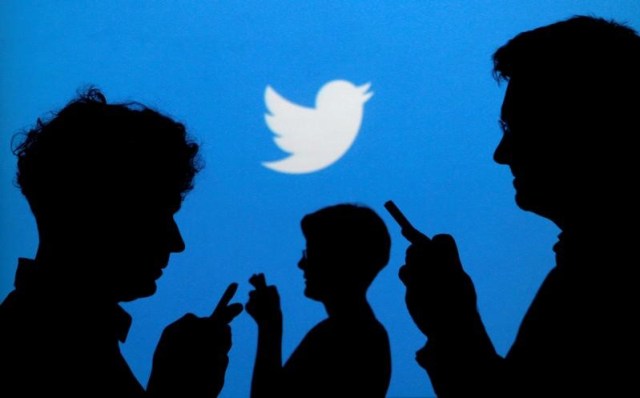 Gente sostiene sus teléfonos móviles tras un fondo en el que se proyecta el logo de Twitter (Foto: Reuters)