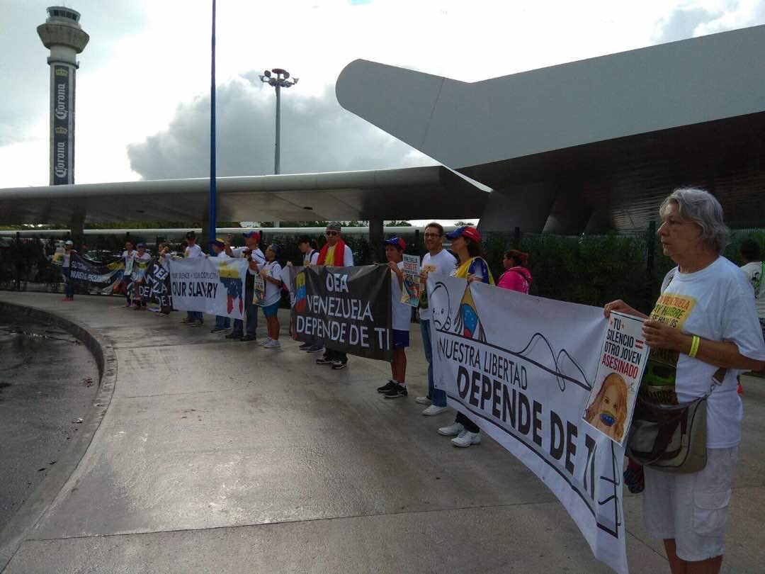 Con pancartas y en silencio, venezolanos reciben a delegaciones de la OEA en Cancún (Fotos)