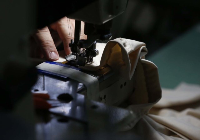 Reina Salas works on clothing for Venezuelan artist and designer Lisu Veg collection "Resistance" in a warehouse in Miami, Florida on June 8, 2017. The models are dressed in scenes of violence in Caracas and handkerchiefs representing the rags used by protesters to protect themselves from police tear gas. It is the "Resistance" collection of Venezuelan fashion designer Lisu Vega. / AFP PHOTO / RHONA WISE