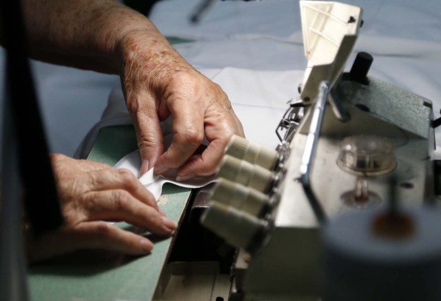 Reina Salas works on clothing for Venezuelan artist and designer Lisu Veg collection "Resistance" in a warehouse in Miami, Florida on June 8, 2017. The models are dressed in scenes of violence in Caracas and handkerchiefs representing the rags used by protesters to protect themselves from police tear gas. It is the "Resistance" collection of Venezuelan fashion designer Lisu Vega. / AFP PHOTO / RHONA WISE