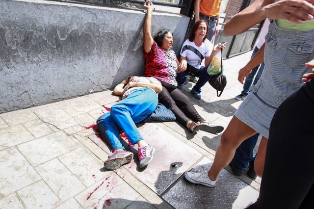 CAR703. CARACAS (VENEZUELA), 16/07/2017.- Dos mujeres yacen en el suelo durante un enfrentamiento entre un grupo de personas adeptas al oficialismo y personas opositoras al gobierno nacional durante la consulta popular hoy, domingo 16 de julio de 2017, en el oeste de Caracas (Venezuela). Dos personas murieron y otras cuatro resultaron heridas de gravedad hoy en el oeste de Caracas después de que un grupo de hombres armados dispararan durante la celebración de la consulta opositora contra el proceso constituyente activado por el Gobierno, informó el jefe de campaña del referéndum. EFE/Nathalie Sayago/ATENCIÓN EDITORES: CONTENIDO GRÁFICO EXPLÍCITO