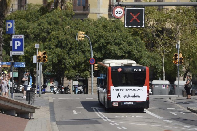 A Barcelona city regular line bus with a message reading in Catalan "We are all Barcelona" waits at a junction in Barcelona on August 21, 2017. Spanish police said on August 21, 2017 that they have identified the driver of the van that mowed down pedestrians on the busy Las Ramblas boulevard in Barcelona, killing 13. The 22-year-old Moroccan is believed to be the last remaining member of a 12-man cell still at large in Spain or abroad, with the others killed by police or detained over last week's twin attacks in Barcelona and the seaside resort of Cambrils that claimed 14 lives, including a seven-year-old boy. / AFP PHOTO / Josep LAGO