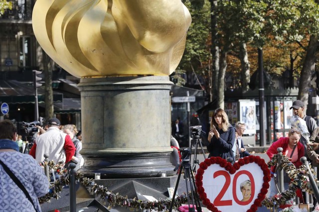 A woman stands near flowers, messages and pictures laid around the Flame of Liberty monument - which became an unofficial memorial for Diana, Princess of Wales who died in a car crash in a nearby tunnel - over the Alma bridge in Paris on August 31, 2017, on the 20th anniversary of the death of the Princess. The life of Diana -- a shy, teenage aristocrat who suddenly became the world's most famous woman -- and her tragic death at 36 still captivates millions across the globe. Diana died in a car crash in Paris in the early hours of August 31, 1997, along with Dodi Fayed, her wealthy Egyptian film producer boyfriend of two months, and a drink-impaired, speeding driver Henri Paul, who was trying to evade paparazzi. / AFP PHOTO / Patrick KOVARIK