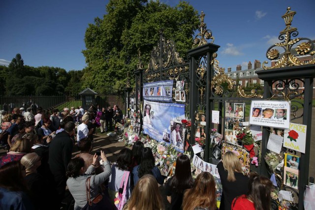 Members of the public gather at the tributes of flowers, candles and photographs outside one of the gates of Kensington Palace in London on August 31, 2017, to mark the 20th anniversary of the death of Diana, Princess of Wales. Fans and friends of Diana, Princess of Wales, were marking 20 years since her death on August 31, 2017 as the nation looked back on the day when the shocking news broke she had been killed in a late-night Paris car crash. / AFP PHOTO / Daniel LEAL-OLIVAS