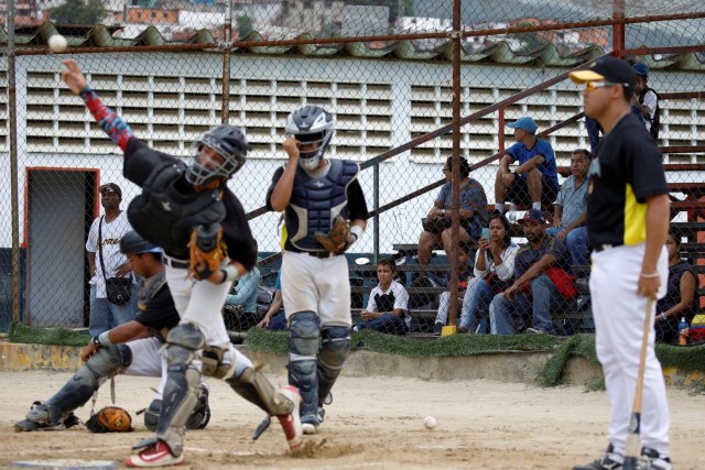 Grey Mejia (C) uses her cellphone to takes pictures to her son Rivaldo Avila (kneeling on L) and the other players, during a baseball showcase in Caracas, Venezuela August 25, 2017. Picture taken August 25, 2017. REUTERS/Carlos Garcia Rawlins