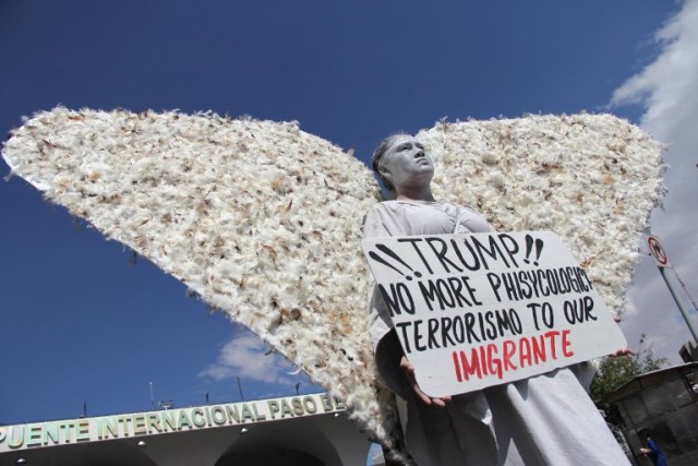 A member of Christian church Salmo 100 dressed as an angel shows a placard addressed to U.S. President Donald Trump in front of drivers crossing the Cordova-Americas International Bridge between Ciudad Juarez, Chihuahua state and El Paso, Texas on September 23, 2017 in Ciudad Juárez, Chihuahua, Mexico. / AFP PHOTO / HÉRIKA MARTÍNEZ