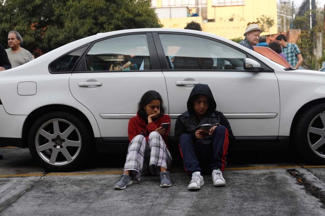 A couple protects themselves in a car inside a residential area after a tremor was felt in Mexico City, Mexico, September 23, 2017. REUTERS/Edgard Garrido