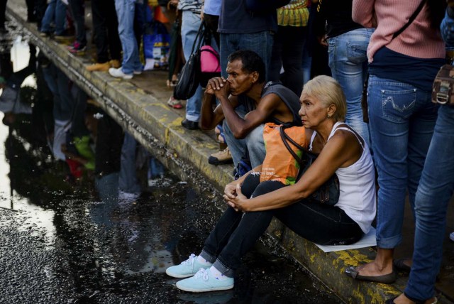  Las personas hacen cola en una parada de autobús en Catia, un barrio de Caracas, el 1 de noviembre de 2017. La gente hace cola hasta cuatro horas para tomar un autobús a casa en Venezuela, donde la movilización por tierra o avión se ha convertido en un dolor de cabeza. / AFP PHOTO / Federico PARRA
