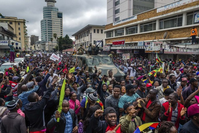People cheer a passing Zimbabwe Defense Force military vehicle during a demonstration demanding the resignation of Zimbabwe's president on November 18, 2017 in Harare. Zimbabwe was set for more political turmoil November 18 with protests planned as veterans of the independence war, activists and ruling party leaders called publicly for President Robert Mugabe to be forced from office. / AFP PHOTO / Jekesai NJIKIZANA