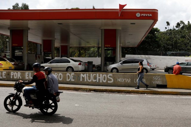 People pass a gas station of Venezuelan state-owned oil company PDVSA in Caracas, Venezuela November 16, 2017. REUTERS/Marco Bello