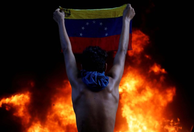 A protester holds a national flag as a bank branch, housed in the magistracy of the Supreme Court of Justice, burns during a rally against Venezuela's President Nicolas Maduro, in Caracas, Venezuela June 12, 2017. REUTERS/Carlos Garcia Rawlins/File Photo      SEARCH "POY GLOBAL" FOR THIS STORY. SEARCH "REUTERS POY" FOR ALL BEST OF 2017 PACKAGES.    TPX IMAGES OF THE DAY