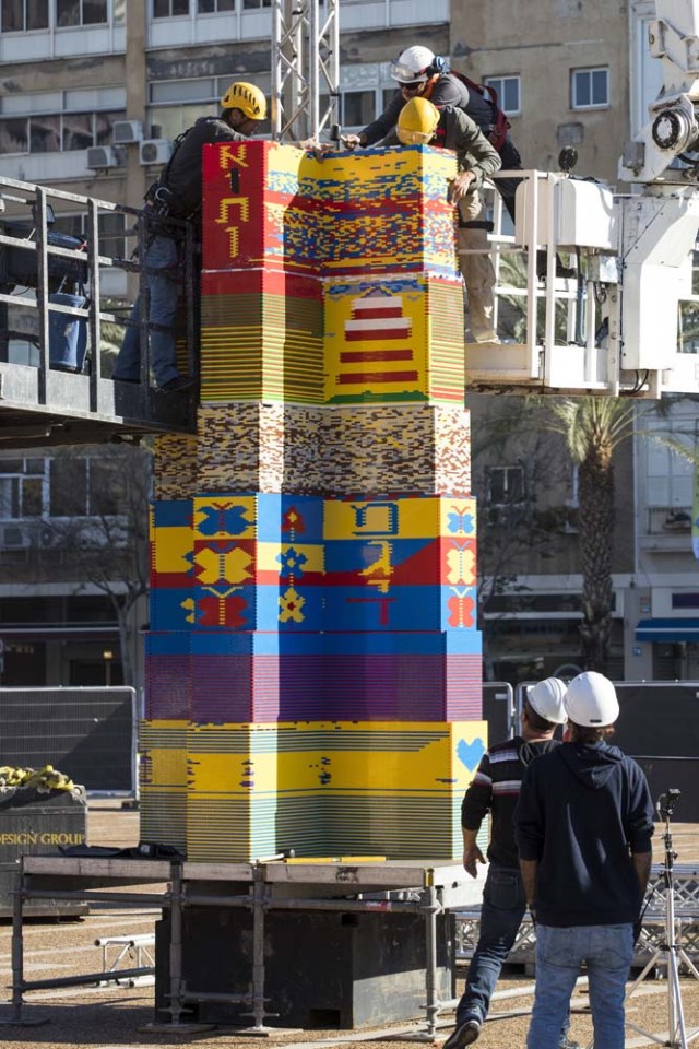 Workers and volunteers help assemble bricks during the construction of a LEGO tower in Tel Aviv's Rabin Square on December 26, 2017, as the city attempts to break Guinness world record of the highest such structure. / AFP PHOTO / JACK GUEZ