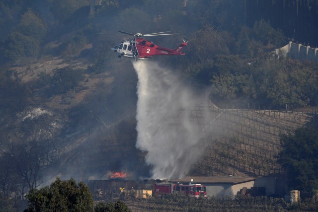 A fire department helicopter makes a water drop building on the vineyard estate of media mogul Rupert Murdoch catches fire during the Skirball fire in Bel Air, a wealthy neighborhood on the west side of Los Angeles, California, U.S., December 6, 2017.      REUTERS/Gene Blevins