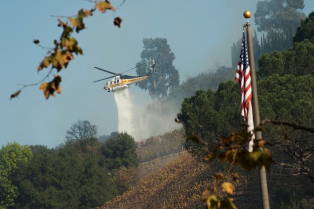 A helicopter drops water on a vineyard owned by Rupert Murdoch damaged by the Skirball fire near the Bel Air neighborhood on the west side of Los Angeles, California, U.S., December 6, 2017.      REUTERS/Andrew Cullen