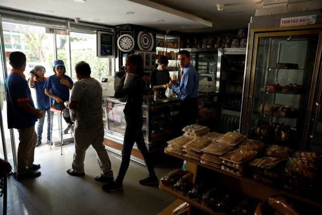 Customers walk out a bakery, during a massive blackout in Caracas, Venezuela December 18, 2017. REUTERS/Marco Bello