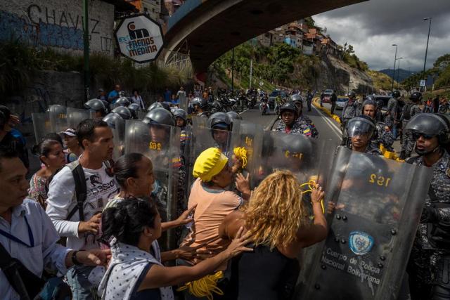 Un grupo de personas protesta frente a miembros de la Policía Nacional Bolivariana (PNB) este jueves 28 de diciembre. EFE/MIGUEL GUTIÉRREZ