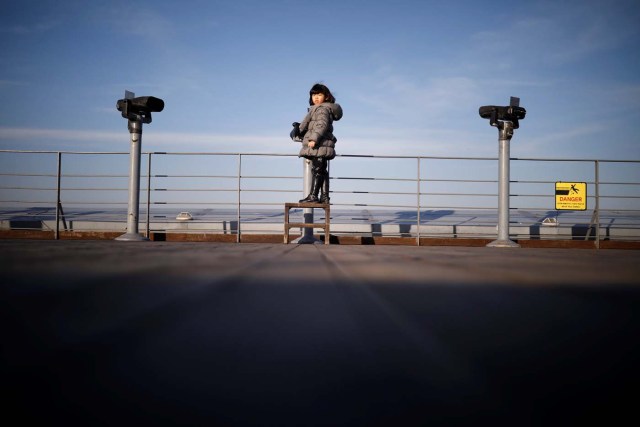 A girl stands between binoculars that look towards the North, near the demilitarized zone separating the two Koreas in Paju, South Korea, January 3, 2018. REUTERS/Kim Hong-Ji