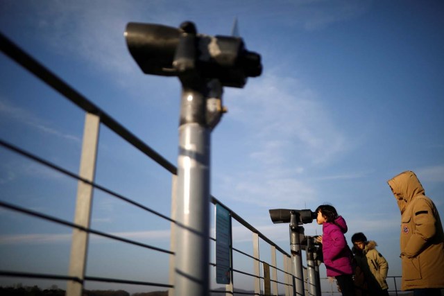 A girl looks toward the North through a pair of binoculars near the demilitarized zone separating the two Koreas in Paju, South Korea, January 3, 2018. REUTERS/Kim Hong-Ji