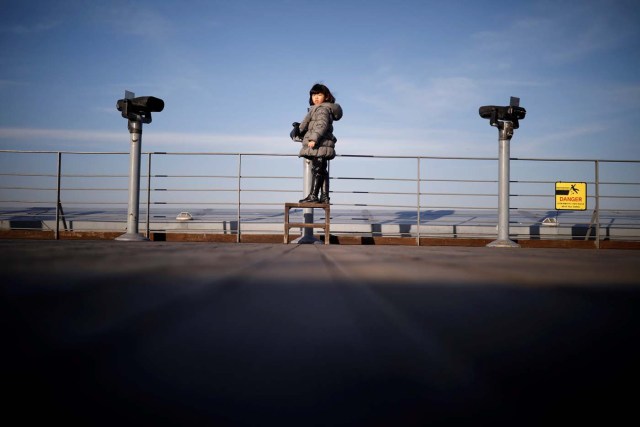 A girl stands between binoculars that look towards the North, near the demilitarized zone separating the two Koreas in Paju, South Korea, January 3, 2018. REUTERS/Kim Hong-Ji TPX IMAGES OF THE DAY