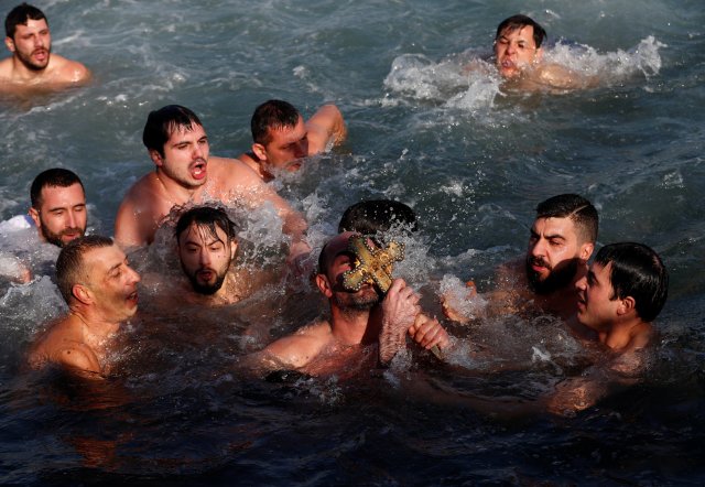 A Greek Orthodox faithful, a pilgrim from Greece, kisses a wooden crucifix as he swims in the Golden Horn in Istanbul, Turkey, January 6, 2018. REUTERS/Murad Sezer