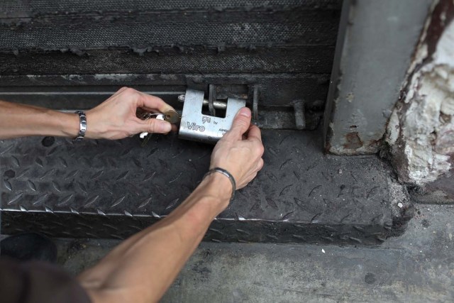 A worker locks a padlock on a security shutter at Arte Paris cafe in downtown Caracas, Venezuela January 16, 2018. Picture taken January 16, 2018. REUTERS/Marco Bello