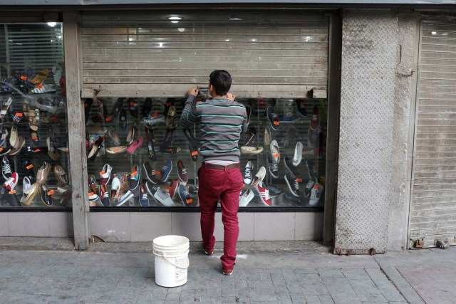 A worker closes the security shutter of a window display at a shoes store in downtown Caracas, Venezuela January 16, 2018. Picture taken January 16, 2018. REUTERS/Marco Bello