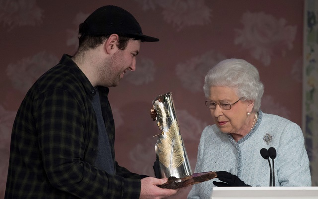 NGH51. LONDRES (REINO UNIDO), 20/02/2018.- La reina Isabel II (d), entrega el premio 'Reina Isabel II al diseño británico' al diseñador británico Richard Quinn (i), tras su desfile durante la Semana de la Moda de Londres (Reino Unido) hoy, 20 de febrero de 2018. EFE/ Neil Hall