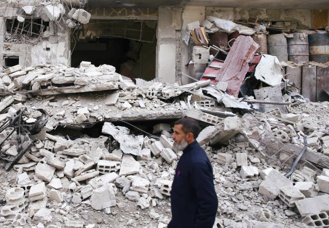 Un hombre camina enfrente de un edificio destruido en la ciudad asediada de Douma, en Guta oriental, Siria. Febrero 25, 2018. REUTERS/Bassam Khabieh